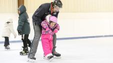This image shows a father and daughter ice skating.