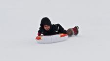 This image shows a young girl sledding down the hill.