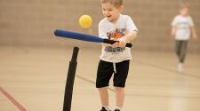 This image shows a boy hitting off the tee at the sports sampler.