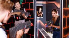 2 men and two women playing laser tag holding laser tag guns and wearing vests.  