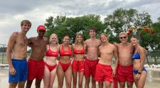 9 lifeguards at the Madison Outdoor Pool standing together lined up for a picture.