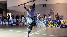 Child in jersey jumping in the air with a hockey stick over his head with parents and kids standing behind the boards cheering kids playing NHL Street on 