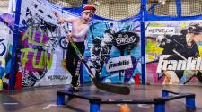 Child practicing stick handling with colorful boards behind her on concrete floor