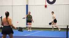 Three women playing pickleball on the Fargo Parks Sports Center pickleball courts