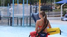 Woman lifeguard looking over the tot sprayground at Island Park Pool 