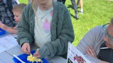 girl dissecting a yellow flower with a tweezer and magnifying glass outside 
