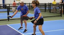 Two senior athletes play pickleball on an indoor court during the North Dakota Senior Games.