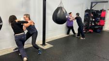 Participants pair up to practice self-defense techniques in a gym setting.