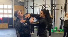 An instructor demonstrates a self-defense technique with a participant in a training space.